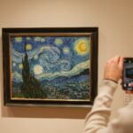 a woman taking a picture of a painting with a cell phone