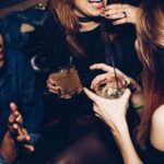 two women talking while holding drinking glasses